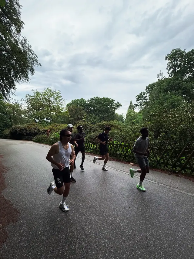 Runners on a grey road under trees