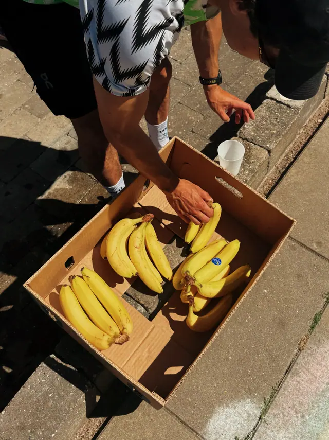 Hands taking bananas from a box on the pavement